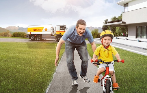 Son riding bicycle father running behind him